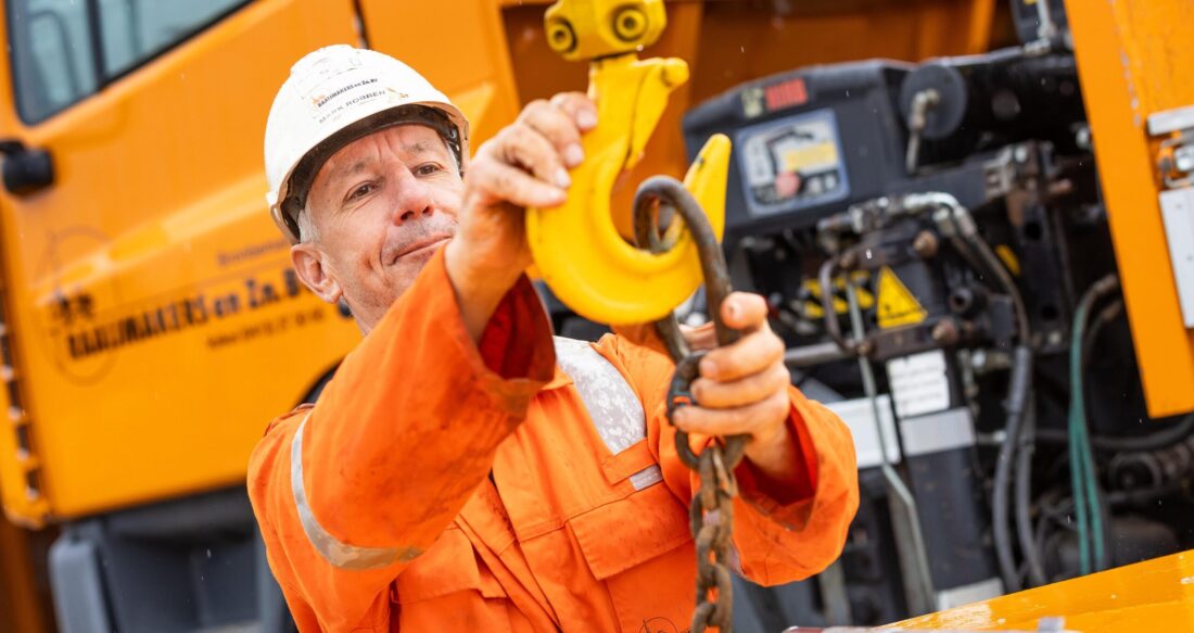 Man die een ketting aan een haak hangt Mark Robben | Raaijmakers