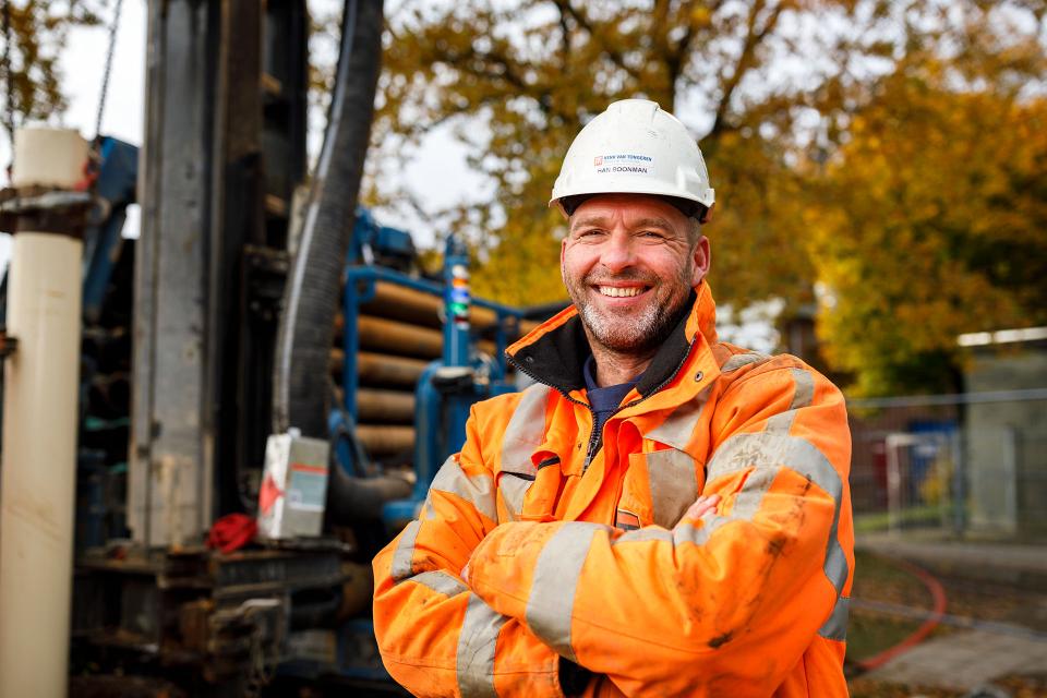 Medewerker met armen over elkaar lachend in de camera